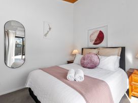 A bedroom with a bed and nightstand at Sunnyside Spa Retreat - Mangawhai Heads