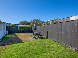 A garden with a picnic table and umbrella at Sunnyside Spa Retreat - Mangawhai Heads