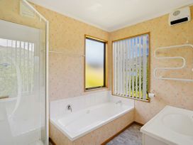 A bathroom with a bathtub, shower, sink, and a window at Lakeside Serenity - Wanaka Holiday Home in Wanaka
