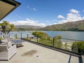 An outdoor patio with chairs and table overlooking a lake at Lakeside Serenity - Wanaka Holiday Home, Wanaka