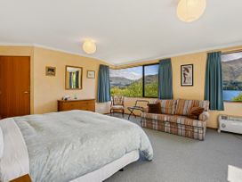 A bedroom with a bed and sofa at Lakeside Serenity - Wanaka Holiday Home in Wanaka
