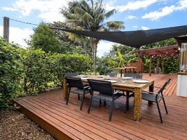 An outdoor dining area with a wooden table and chairs at Matapouri Hideaway - Matapouri