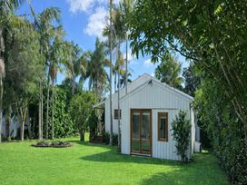 A house surrounded by palm trees and grass at Matapouri Hideaway - Matapouri