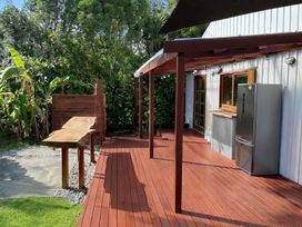 An outdoor deck with a table and refrigerator at Matapouri Hideaway - Matapouri