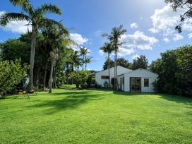 A garden with a house and palm trees at Matapouri Hideaway in Matapouri