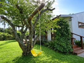 A yellow swing hanging from a tree in an outdoor area at Matapouri Hideaway - Matapouri