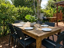 A dining area with a wooden table and chairs at Matapouri Hideaway - Matapouri