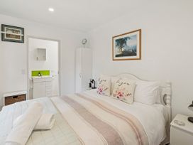 A bedroom with a bed and wardrobe at Bellbird Cottage - Lake Taupo Bach in Waitahanui