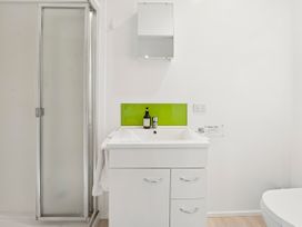 A bathroom with a shower, sink, and mirror at Bellbird Cottage - Lake Taupo Bach Waitahanui