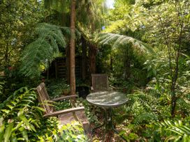 A garden with chairs and a table under trees at Bellbird Cottage - Lake Taupo Bach in Waitahanui