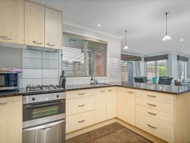A kitchen with a microwave, gas stove, and kitchen sink at Putt it at Pauanui - Pauanui