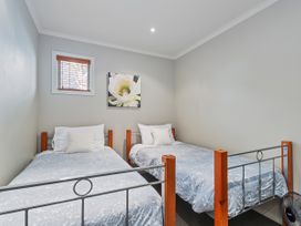 A bedroom with two beds and wall art at Putt it at Pauanui - Pauanui