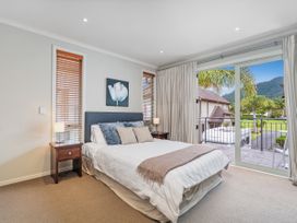 A bedroom with a bed and sliding door to the balcony at Putt it at Pauanui - Pauanui