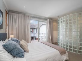A bedroom with a bed and glass block wall at Putt it at Pauanui - Pauanui
