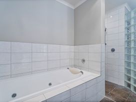 A bathroom featuring a bathtub and a shower area at Putt it at Pauanui - Pauanui