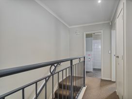 A hallway with a staircase and access to a bathroom at Putt it at Pauanui - Pauanui