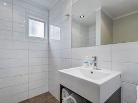 A bathroom with a sink and mirror at Putt it at Pauanui - Pauanui