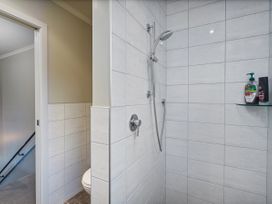 A shower with wall tiles and a toilet in the bathroom at Putt it at Pauanui - Pauanui