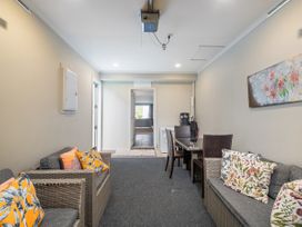 A living room with seating and a dining table at Putt it at Pauanui - Pauanui