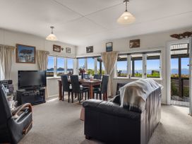 A living room with a television and dining table at Raisin Town - Marahau Bach in Marahau