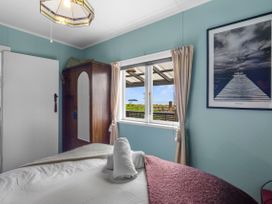 A bedroom with a bed, wardrobe and window at Raisin Town - Marahau Bach Marahau