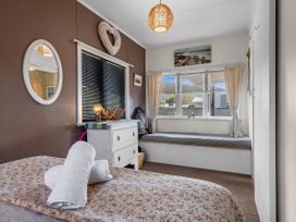 A bedroom with a bed and window at Raisin Town - Marahau Bach, Marahau