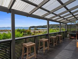 An outdoor terrace with stools and a view of the water at Raisin Town - Marahau Bach in Marahau