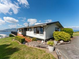 A house with a deck and surrounding greenery at Heights Haven - Acacia Bay Holiday Home Acacia Bay