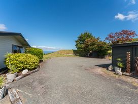 An outdoor area with a house, bushes, trees, and a shed at Heights Haven - Acacia Bay