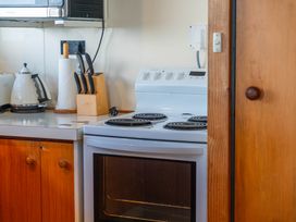 A kitchen with a stove, microwave, kettle, and knife block at Heights Haven - Acacia Bay Holiday Home Acacia Bay