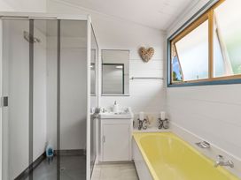 A bathroom with a shower, bathtub, sink and mirror at Heights Haven - Acacia Bay Holiday Home
