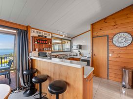 A kitchen with bar stools and appliances at Heights Haven - Acacia Bay Holiday Home Acacia Bay