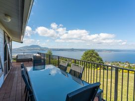 An outdoor area with a table and chairs overlooking a lake at Heights Haven - Acacia Bay Holiday Home