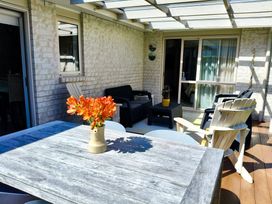 An outdoor patio with a table and chairs at Modern Beach Break - Waihi Beach