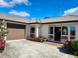 An entrance with a garage door and plants at Modern Beach Break - Waihi Beach Holiday Home