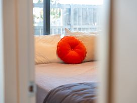 A bed with an orange pillow and white pillows at Lake Magic - Motuoapa Holiday Home Motuoapa