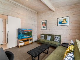 A living room with a TV and sofas at Beachfront Escape - Snells Beach Holiday Home in Matakana