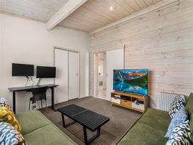 A living room with a sofa, coffee table, and television at Beachfront Escape - Snells Beach Holiday Home, Matakana