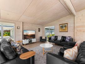 A living room with a television and sofas at Beachfront Escape - Snells Beach Holiday Home Matakana