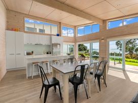 A kitchen with a dining table and chairs at Beachfront Escape - Snells Beach Holiday Home Matakana