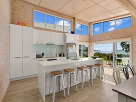 A kitchen with an island and stools at Beachfront Escape - Snells Beach Holiday Home Matakana