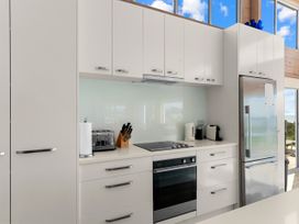 A kitchen with cabinets and appliances at Beachfront Escape - Snells Beach Holiday Home, Matakana
