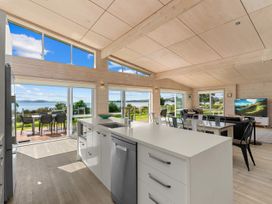 A kitchen with an island counter and living area at Beachfront Escape - Snells Beach Holiday Home Matakana
