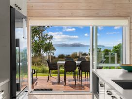 A dining area with a view of the ocean at Beachfront Escape - Snells Beach Holiday Home Matakana