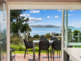 An outdoor area with chairs and table overlooking the sea at Beachfront Escape - Snells Beach Holiday Home Matakana