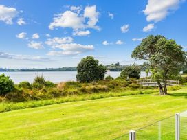 A view of a lake with grass and trees at Beachfront Escape - Snells Beach Holiday Home Matakana