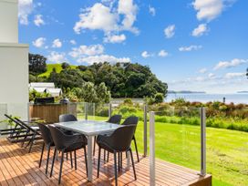 An outdoor dining area with a table and chairs at Beachfront Escape - Snells Beach Holiday Home Matakana