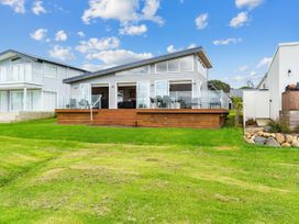 A house with a deck and lawn at Beachfront Escape - Snells Beach Holiday Home Matakana