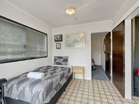 A bedroom with a bed, table, and paintings at Central Spacious Family House - Paihia