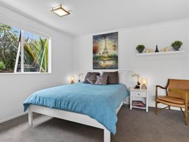 A bedroom with a bed, nightstand, and artwork at Little Pearl of Vista Verano - Mangawhai Village